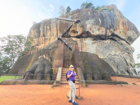 Person climbing stairs on a large rock formation known as Sigiriya.