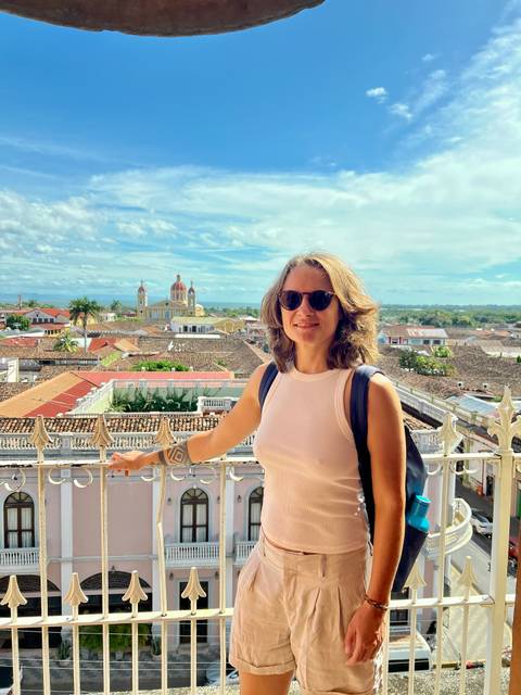       Person posing in front of a cityscape with a cathedral.
  