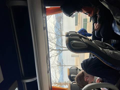 View from inside a bus with people looking outside at a lake.