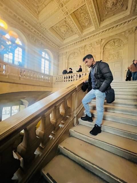 Man standing by a staircase inside a historic building.