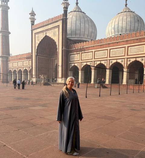 Person standing in front of a grand mosque with intricate architectural details.