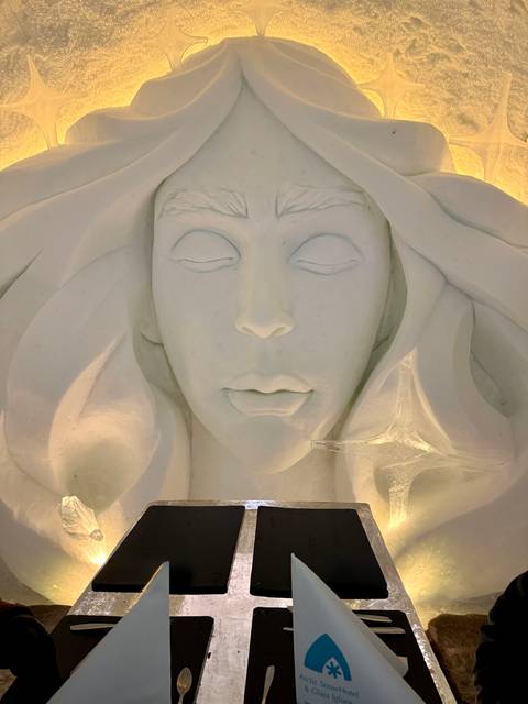 Close-up of an ice sculpture depicting a serene face with flowing hair.