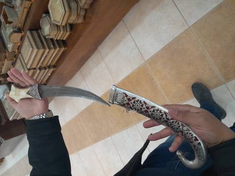 Close-up of a hand holding a traditional dagger with ornate designs.