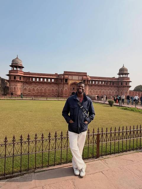       Person standing in front of a historic red fort.
  