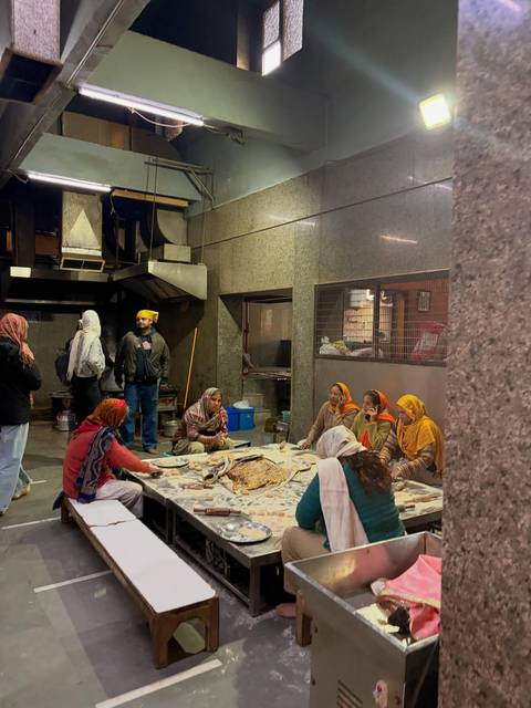       Group of people in traditional attire sitting on the floor making food.
  