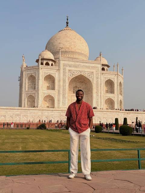       Person posing in front of the Taj Mahal.
  