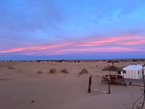 Desert campsite with colorful sunset and tents.