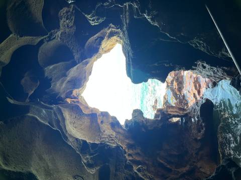       Natural rock archway opening to a view of the ocean.
  