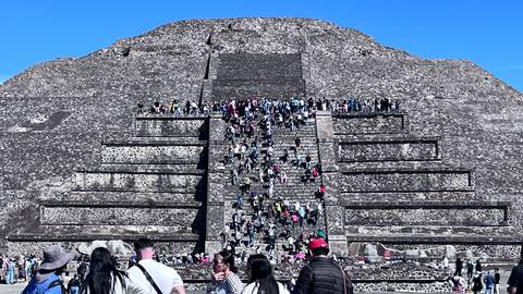       Large group of people climbing the steps of an ancient pyramid.
  