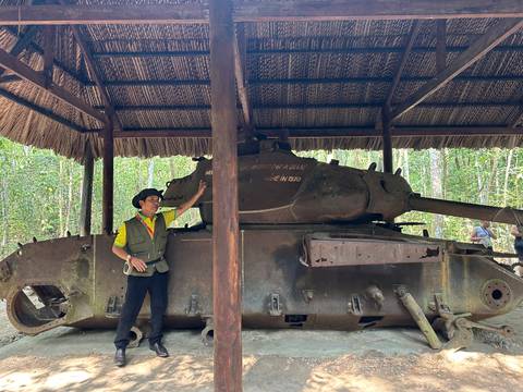 Guide showing an old tank under a thatched shelter