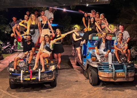 People posing on top of two colorful jeepneys at night