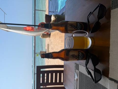 Two bottles of beer on a table by the ocean.