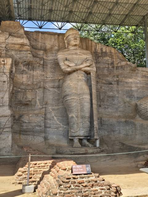 Statue of a standing Buddha carved into a rock.