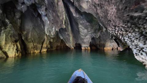 Inside a cave with a boat on the water.