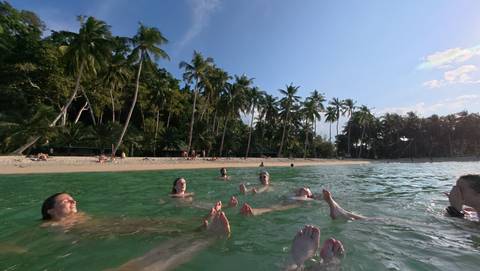 People floating in clear water at a beach.