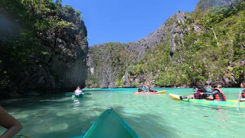 Group kayaking in clear water surrounded by cliffs.