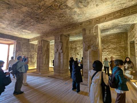 Interior of a temple with carvings and tourists.