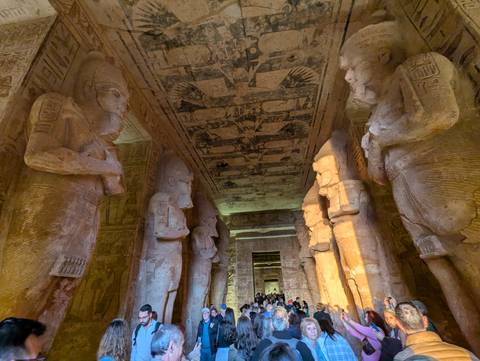 Statues within a majestic ancient temple with visitors.