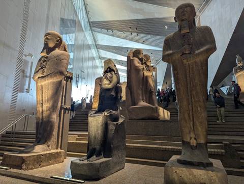 Museum interior with large statues and tourists.