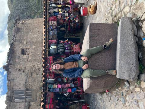       Person sitting on a stone block in front of a market stall.
  