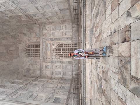       Visitor standing at the entrance of the iconic Taj Mahal with detailed white marble.
  