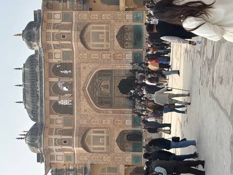       Crowded scene in front of a historical fort entrance with ornate decorations.
  
