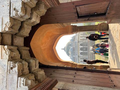 Crowd walking through an old monument archway.