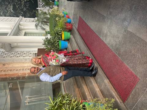 Couple posing with a bouquet of flowers on building steps.