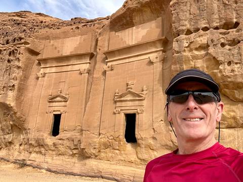 Selfie of a man in front of ancient rock carvings.