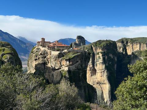 Monastery perched on cliffs surrounded by a mountainous landscape.