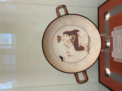 Ancient Greek pottery with intricate painted designs displayed in a museum.