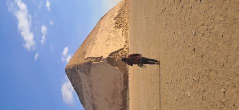       Individual walking towards a desert pyramid under a clear sky.
  