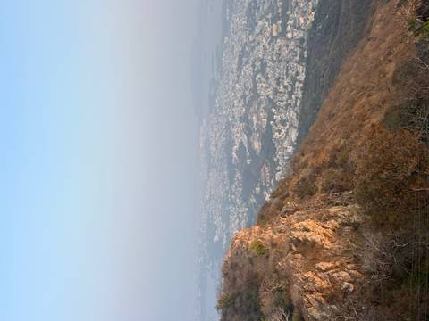 Aerial view of a cityscape surrounded by hills during sunset.