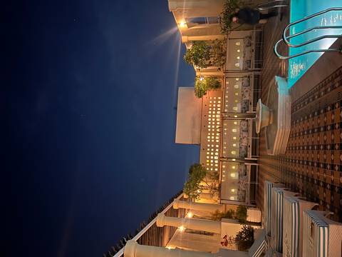 Outdoor patio area at night with seating and a pool.