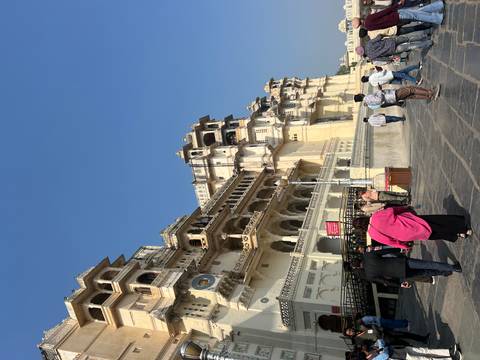 People walking in front of a large historic palace.