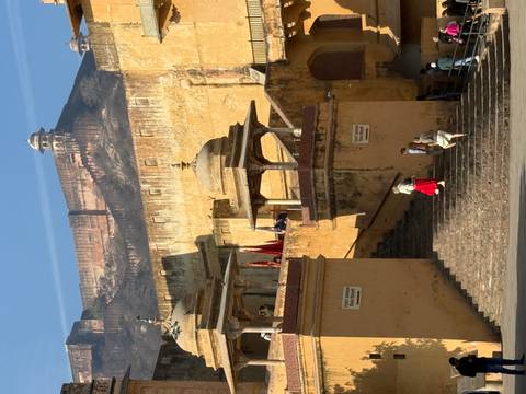       Large fort with tourists on the steps and a clear blue sky.
  