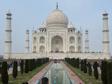       Iconic view of the Taj Mahal with tourists in the foreground.
  