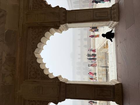       Tourists inside a historic site with arched windows and foggy view outside.
  