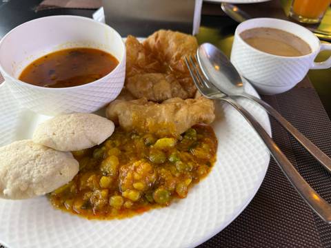       Breakfast plate with Indian dishes and a cup of coffee.
  