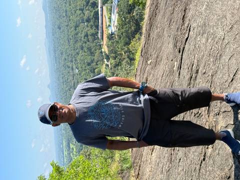 A person on a hill overlooking a vast forested area.