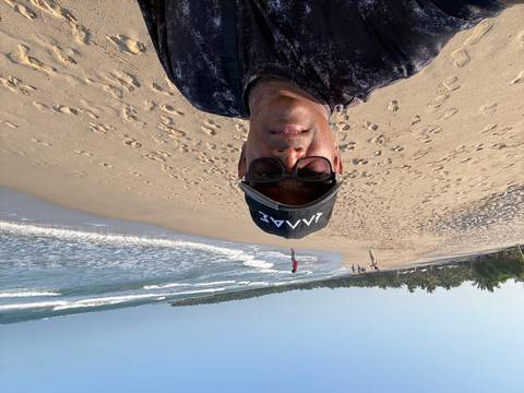       A person on a beach with ocean waves and palm trees.
  