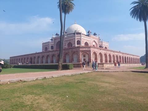       Historic building with pedestrian visitors and palm trees.
  