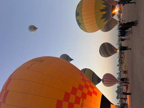 Hot air balloons rising at dawn with people on the ground.