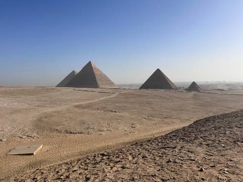 Pyramids of Giza under a clear sky in a sandy landscape.