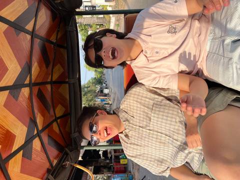 Two friends laughing in a tuk-tuk on a sunny day.