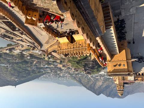       View from above of Amer Fort with hills in the background.
  