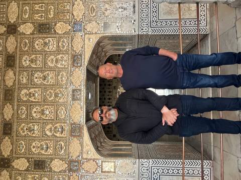       Two men stand before intricate mirrored mosaic walls inside Amber Fort's Sheesh Mahal.
  