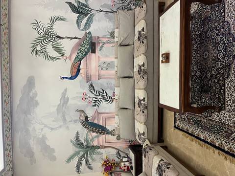       Tastefully decorated sitting area with peacock mural, ornate rug and light-colored sofa.
  