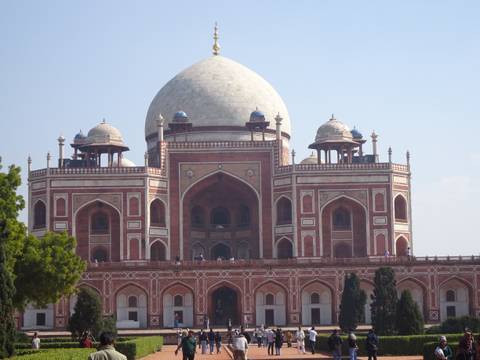       Symmetrical view of red sandstone Humayun's Tomb with blue sky background.
  
