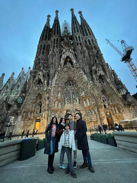       Family standing in front of the ornate Nativity façade of Sagrada Família at dusk.
  